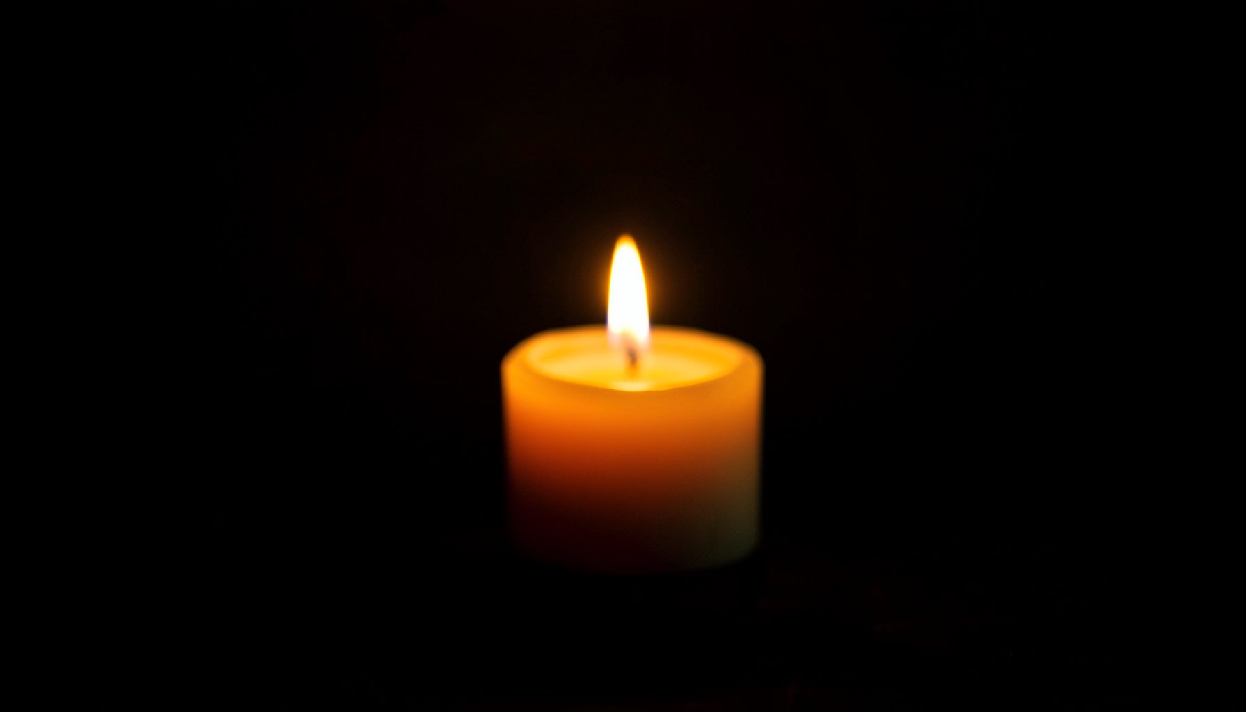 Warm candlelight glowing against a dark background, with soft amber and deep brown tones creating an intimate, reflective atmosphere.