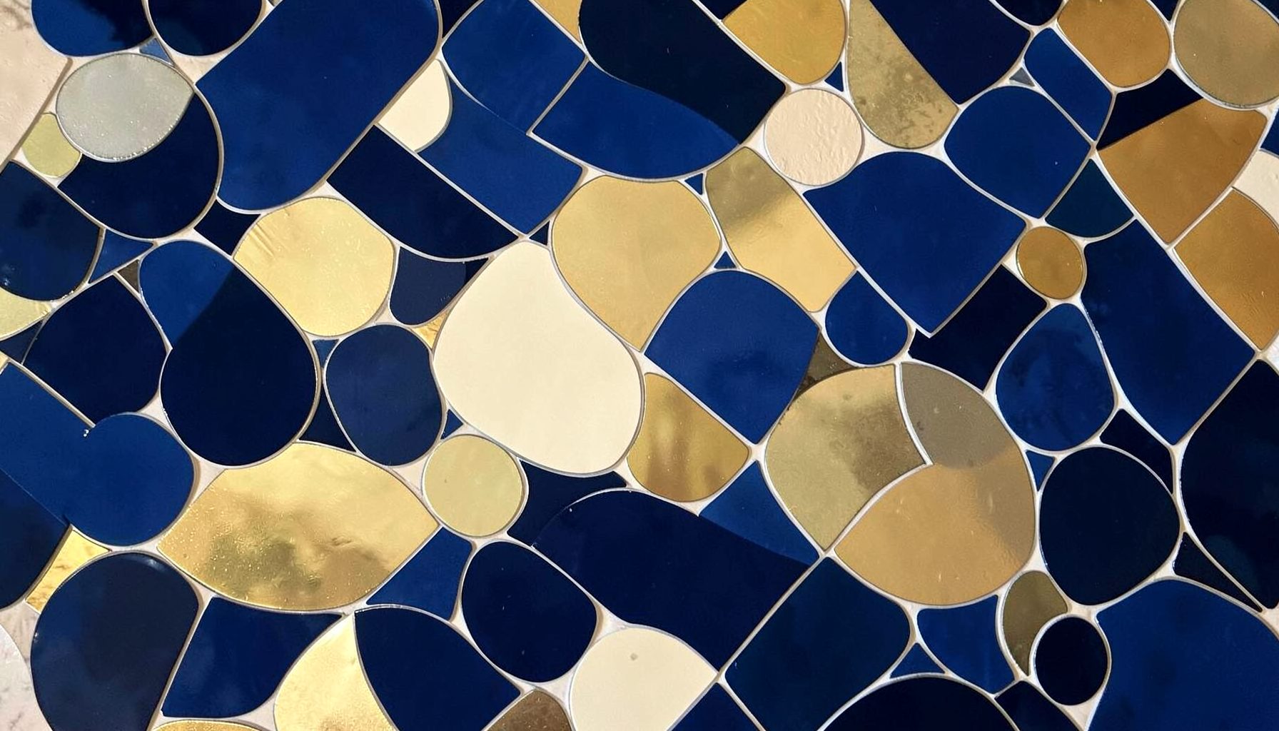 Warm abstract mosaic of overlapping circles in deep blue, gold, and cream tones, suggesting community connection and shared light.
